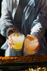 A bartender pouring a vibrant margarita into a chilled coupe glass, orange peel twist and salt rim visible, moody bar lighting with elegant presentation and negative space.