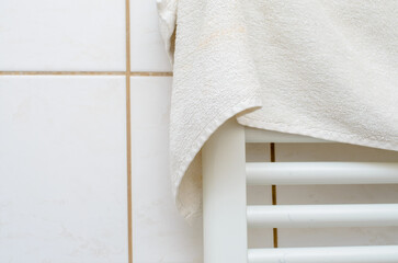 Soft white terry cloth towel drying on a modern heated rack in bathroom
