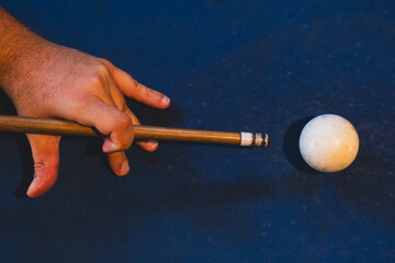 Close-up of cue stick striking the white ball in billiards. Hitting the cue ball on a blue pool...