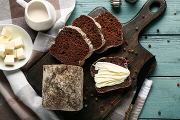 Sliced bread with butter, peppercorns and jug of cream on wooden background