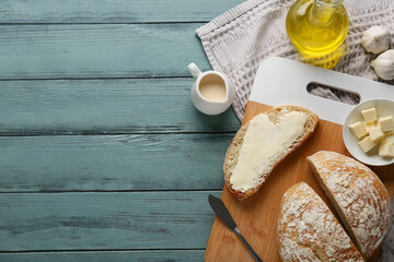 Sliced bread with butter, garlic and jug of cream on wooden background