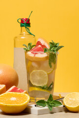 Glass with cool drink garnished with mint, lemon and grapefruit.
