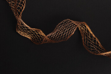 Gold, bronze metallic copper braided wave wire on black. Abstract light, shadow texture background.
