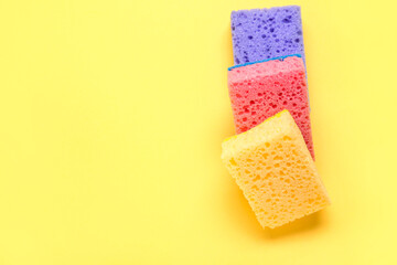 Colorful cleaning sponges on yellow background
