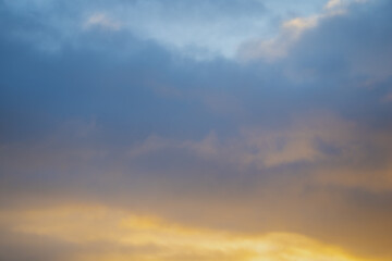 Colorful sky at sunset with layered blue and golden clouds, showing soft gradient of natural light and atmospheric depth during transition from daylight to evening in tranquil weather scene
