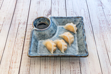 Japanese dumplings filled with beef, broccoli, and carrots, accompanied by sesame sauce
