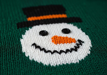 Close-up of knitted ugly Christmas sweater with snowman face pattern
