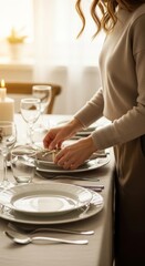 A woman in a warm sweater arranges the elegant table setting with plates, silverware, and wine glasses, creating a cozy and inviting atmosphere for a holiday dinner or special occasion.