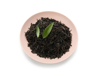 Plate with dry black tea and leaves on white background