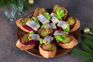 Bruschetta with herring, beetroot and pickled cucumber on brown plate
