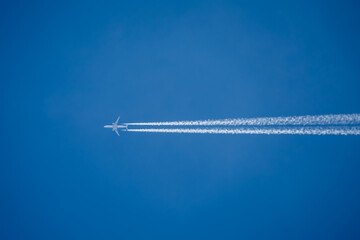 twin engined jet liner aircraft with contrails, in flight at high altitude, clear blue sky