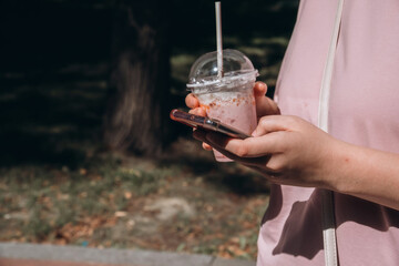 Person Holding Phone and Drink in a Park Setting