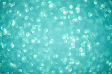 Defocused lights from turquoise glitter as a background.