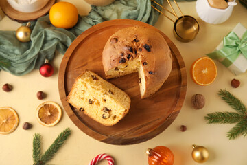 Wooden stand with cut Panettone and Christmas decor on beige background