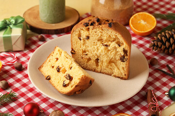 Plate with cut Panettone, gift box and Christmas decor on napkin