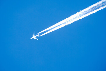 twin engined jet liner aircraft with contrails, in flight at high altitude, clear blue sky