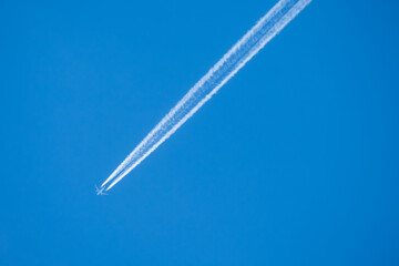 twin engined jet liner aircraft with contrails, in flight at high altitude, clear blue sky