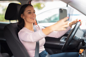 Woman taking selfie while driving car on road