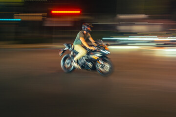Biker riding motorcycle bike in night city. Blurred motion.