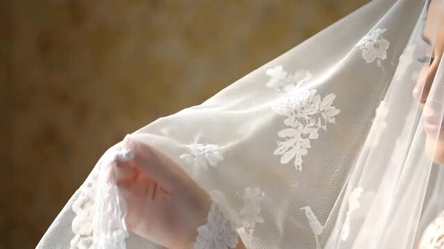 Close up portrait of a beautiful smiling bride with dark hair and make up gently covered by a white lace veil