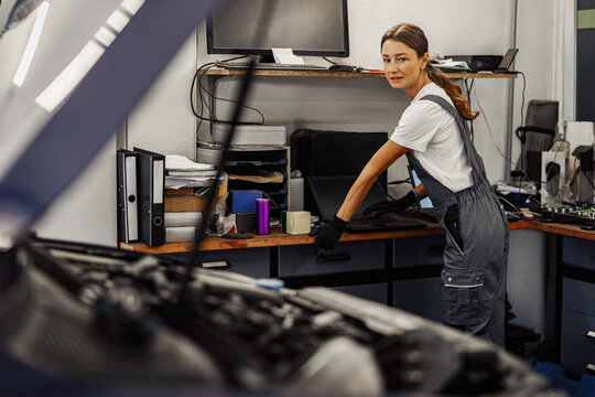 A skilled female mechanic working on a vehicle in a modern auto repair shop, demonstrating her expertise - Powered by Adobe