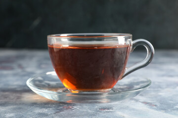 Cup of tasty black tea on grey grunge background, closeup