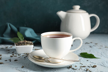 Cup of tasty black tea on blue grunge background, closeup
