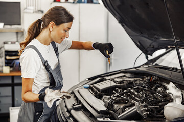 In a bustling automotive repair shop, a skilled female mechanic diligently inspects a vehicles engine