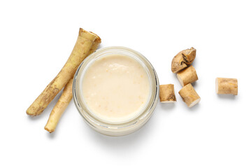 Jar of horseradish sauce with root on white background