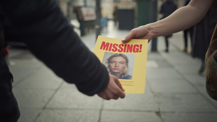 Missing person flyer exchange on urban street, search efforts, community involvement, public awareness, sharing information, collaborative action, city background, concern for safety