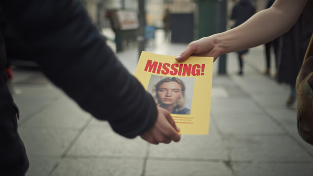 Missing person flyer exchange on urban street, search efforts, community involvement, public awareness, sharing information, collaborative action, city background, concern for safety