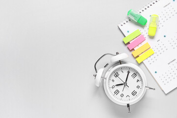 Calendar with alarm clock, markers and stickers on grey background