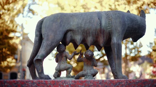 Historic bronze statue of the Capitoline Wolf with Romulus and Remus on a red marble pedestal in front of the National History Museum of Moldova