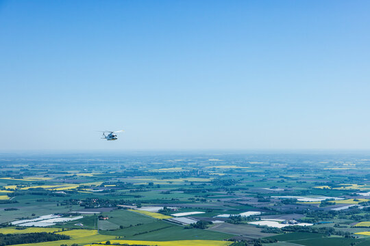 Large helicopter flying over the Baltic Sea with landscape and wind farms in the background.