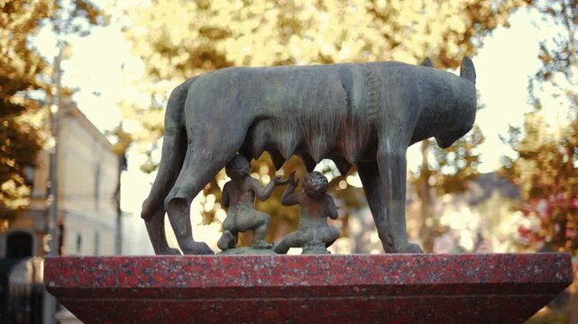 Historic bronze statue of the Capitoline Wolf with Romulus and Remus on a red marble pedestal in front of the National History Museum of Moldova