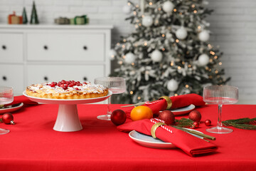 Stylish table setting for Christmas dinner with delicious cranberry pie, fir tree branches and balls