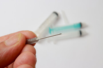 Man holding a medical syringe needle between his fingers 
