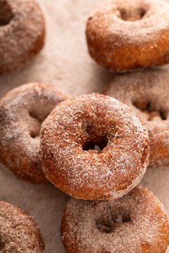 Apple cider or pumpkin spice donuts being covered in cinnamon sugar after baking