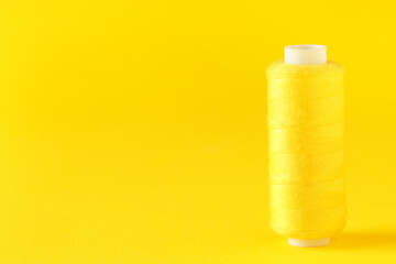 Spool of thread on yellow background