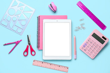 Set of school stationery and tablet computer on blue background