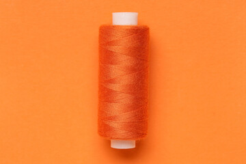 Spool of thread on orange background