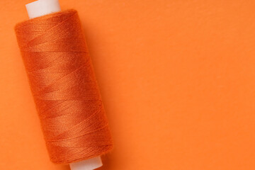 Spool of thread on orange background