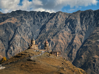Gergeti Trinity Church on a mountain ridge in the Caucasus Mountains, Georgia. Drone view of the ancient stone monastery and high mountain landscape.