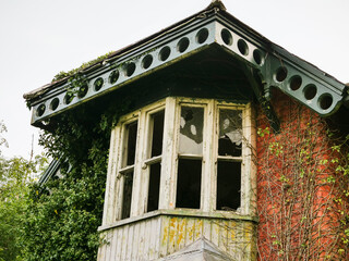 Broken glass in a window in an old and abandoned building. Red brick home with fine decorative elements.