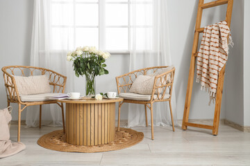 Interior of living room with armchairs, coffee table and white roses in vase