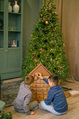 Children open Advent calendar gift boxes in the living room by the Christmas tree. There's a surprise in every box every day of December.  Waiting for the new year