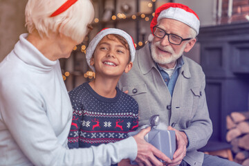 Cute little boy celebrating Christmas eve with grandparents at home with gifts. Senior old elderly...