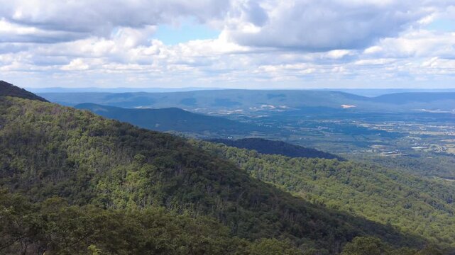 A scenic overlook reveals layers of rolling hills and a distant valley under a clear blue sky near Shenandoah National Park, Virginia, U.S.A