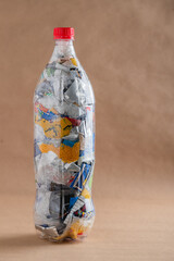 Plastic ecobrick bottle filled with compacted waste against neutral background
