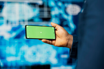 Black IT technician shows smartphone with chroma key screen, examining predictive analytics and neural networks for data processing automation and high tech innovation. Cybernetics.